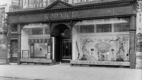 A Kodak store window displays cameras and fall leaves, with information on how to photograph during that season.  
