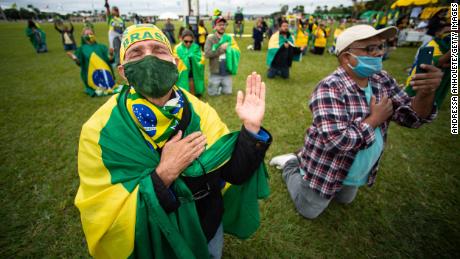 Apoiadores do presidente Jair Bolsonaro rezam enquanto andam de motocicleta e protestam contra o Congresso Nacional e o Supremo Tribunal Federal por medidas de contenção durante a pandemia do coronavírus (COVID-19) antes do Congresso Nacional em 9 de maio de 2020 no Brasil.