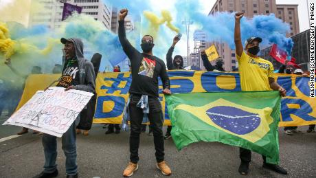 Manifestantes usando máscaras erguem os punhos na Avenida Paulista durante um protesto em meio à pandemia do coronavírus (COVID-19) em 14 de junho de 2020 em São Paulo, Brasil.