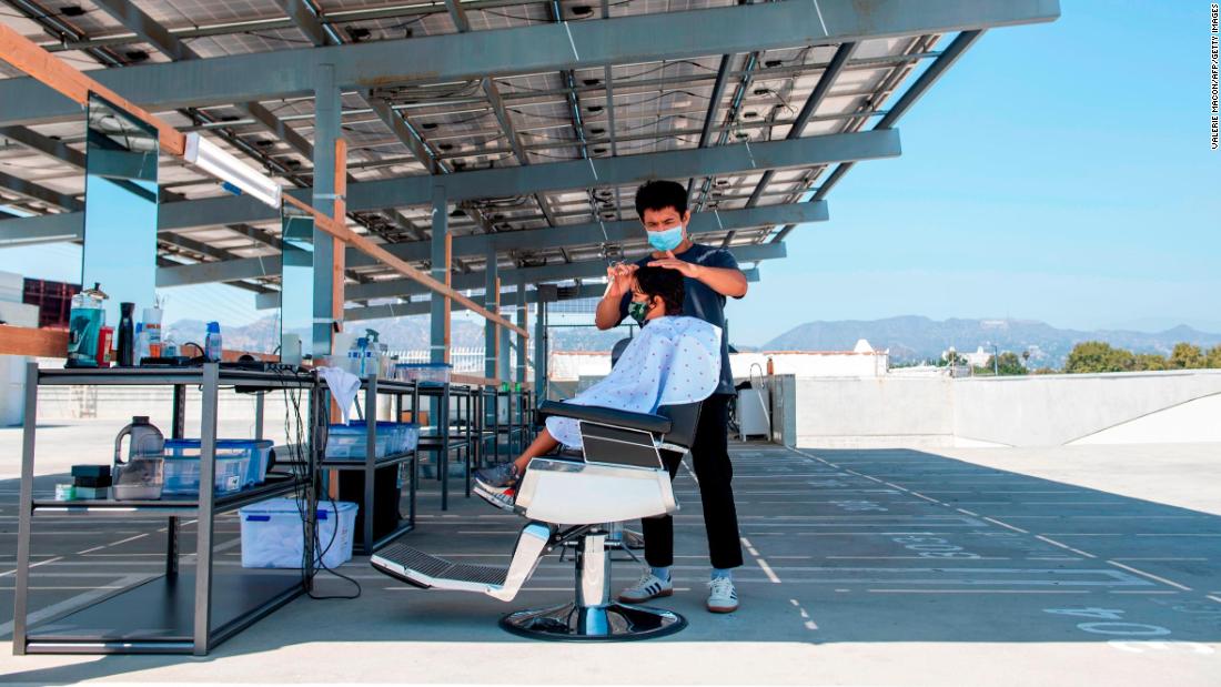 A stylist from Grey Matter LA cuts a client&#39;s hair on a rooftop parking lot in Los Angeles on August 4.