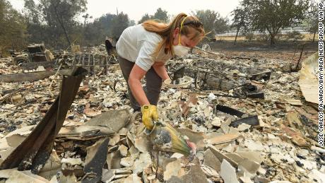 Sarah Hawkins finds a vase in the rubble after her home was destroyed by a fire in Vacaville, California.