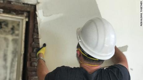 A contractor removes drywall from a home being repaired with donations from Rebuilding Together.