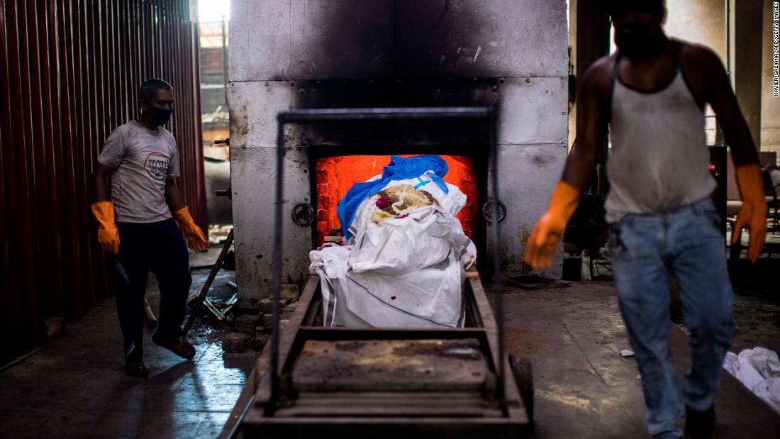 Workers in New Delhi prepare to cremate the body of a coronavirus victim on August 22.