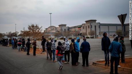Customers queue while waiting for the opening of a liquor shop in Johannesburg, on August 18