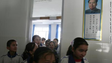 Students walk past a portrait of China&#39;s late Chairman Mao Zedong at a bilingual middle school for Uyghur and Han Chinese students in Hotan, Xinjiang in 2006.
