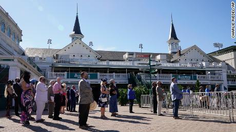 A few guests stand during the nation anthem before the  running of the Kentucky Derby on Saturday. Few people were allowed inside because of health concerns.