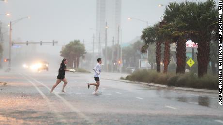 GULF SHORES, ALABAMA - SEPTEMBER 15: People run across a road through the rain and wind as the outer bands of Hurricane Sally come ashore on September 15, 2020 in Gulf Shores, Alabama. The storm is bringing heavy rain, high winds and a dangerous storm surge from Louisiana to Florida. (Photo by Joe Raedle/Getty Images)