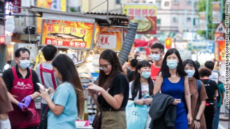 People wearing protective masks walk past food stalls at the Ningxia Night Market in Taipei, Taiwan, on July 30, 2020.