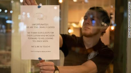 A man puts a sign in the window of the Corner House pub in Cardiff, Wales in March.