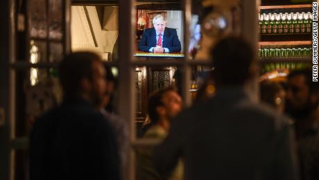 Drinkers at the Westminster Arms pub in London watch as British PM Boris Johnson makes a televised address to the nation on Tuesday.