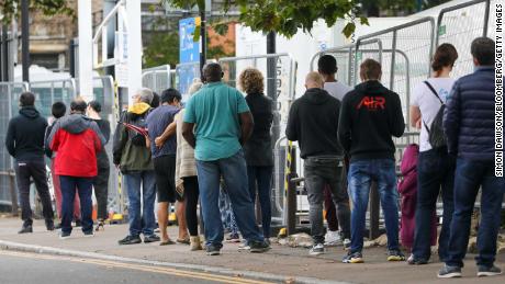 Visitors stand in line at a coronavirus walk-in testing center in Edmonton, London, on Wednesday.