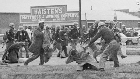 In this March 1965 photo, a state trooper swings a billy club at John Lewis, right foreground, chairman of the Student Nonviolent Coordinating Committee, to break up a civil rights voting march in Selma, Alabama. Lewis sustained a fractured skull. 