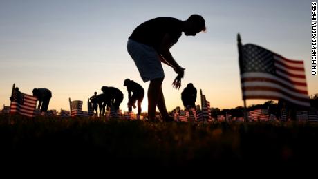Volunteers with the &#39;COVID Memorial Project&#39; install 20,000 American flags on the National Mall.