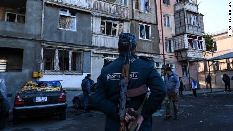 A police officer stands in front of a damaged apartment building in Stepanakert, during the ongoing conflict.