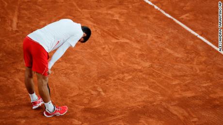 Djokovic leans on his racket in the quarterfinal match against Carreno Busta.