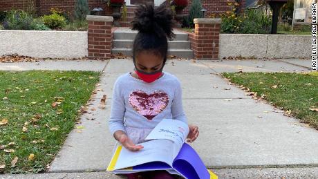 A child reading one of the books from a Little Free Library.
