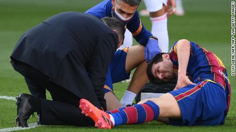 Messi receives medical attention after being tackled during the game against Real Madrid.