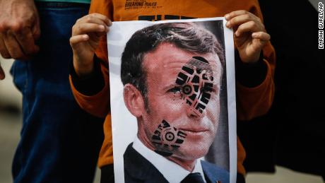 Un niño sostiene una foto de Emmanuel Macron, que fue marcada con la marca de un zapato durante una protesta contra Francia el 25 de octubre en Estambul.
