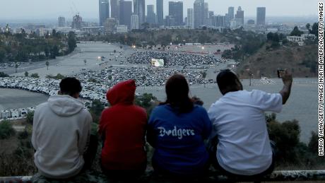 Dodgers-Fans versammeln sich auf einem Aussichtspunkt, während die Leute am 23. Oktober 2020 in Los Angeles, Kalifornien, an einem Drive-In-Screening von Spiel 3 der 2020 World Series zwischen den Los Angeles Dodgers und den Tampa Bay Rays auf einem Parkplatz im Dodger Stadium teilnehmen.
