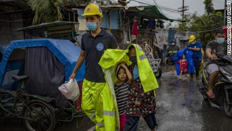 MANILA, PHILIPPINES - NOVEMBER 01: A rescue worker covers children in a raincoat as they evacuate before Typhoon Goni hits on November 1, 2020 in Manila, Philippines. Super Typhoon Goni, this year&#39;s most powerful storm in the world,  has made landfall in the Philippines with wind gusts of up to 165 miles per hour early Sunday. At least two people have been killed so far and hundreds of thousands have been evacuated ahead of the storm. (Photo by Ezra Acayan/Getty Images)