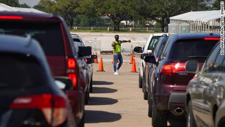 An election worker guides voters in cars at a drive-through mail ballot drop-off site at NRG Stadium in Houston, Texas, l'anno scorso.