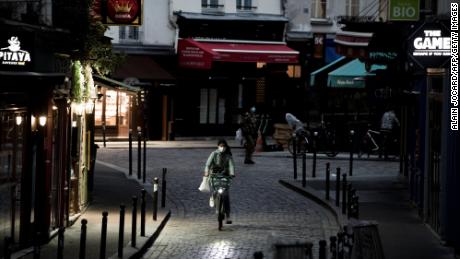 A woman rides a bike along an empty street in the district of St. Michel in Paris on November 3, the fifth day of France&#39;s lockdown.
