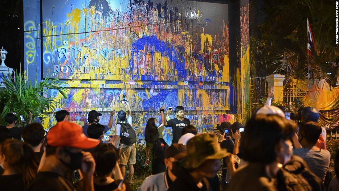 11 월 방콕 경찰 본부의 페인트 칠한 간판 옆에서 민주화 시위대가 사진을 찍고있다 18.
