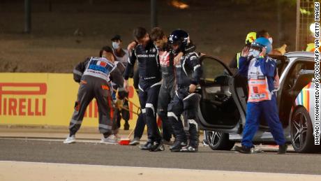 Stewards and medics attend to Grosjean after the crash. 