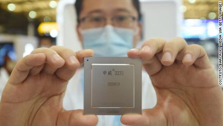 یک کارمند SMIC آخرین تراشه سرور خانگی را در نمایشگاه بین المللی China International Semiconductor Expo 2020 به نمایش می گذارد. SMIC می گوید نیمه هادی های آن برای مصارف غیرنظامی و تجاری است و هیچ ارتباطی با ارتش چین ندارد.