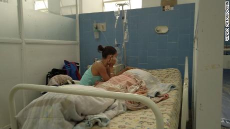 Una mujer fotografiada en el Hospital Vargas en Caracas, Venezuela con su padre de 69 años, a quien le dijo a CNN que sufre de desnutrición y comparte una sala con un paciente de Covid-19 a pesar de su sistema inmunológico comprometido.
