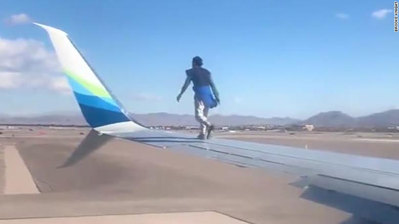 A man was taken into custody after he climbed onto the wing of a airplane preparing to takeoff in Las Vegas