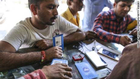 Ein Kunde hält ein SIM-Kartenpaket in der Hand, während er darauf wartet, sein Mobiltelefon am 24. Oktober 2016 in einem Geschäft in Mumbai, Indien, mit dem Mobilfunkanbieter Reliance Jio, dem Mobilfunknetz von Reliance Industries, zu verbinden. 