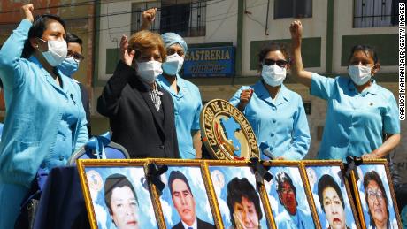 Trabajadores de la salud en la ciudad montañosa de Puno en los Andes, protestan con fotos de sus compañeros de trabajo que murieron durante la pandemia en agosto.