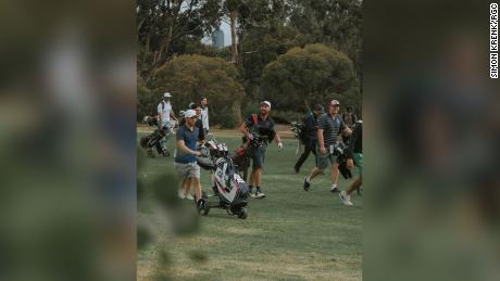 Die Spieler laufen während einer Runde zwischen Random Golf Club-Fans den Fairway entlang. 