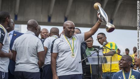 Cheftrainer Pitso Mosimane von Mamelodi Sundowns hält die Trophäe, als das Team am Flughafen Tambo ankommt, nachdem es am 26. Oktober 2016 in Johannesburg, Südafrika, zum CAF Champions League-Meister 2016 gekrönt wurde.