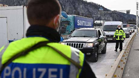 Ein Grenzpolizist bewacht die Grenze zu Österreich, während Autos nach Deutschland fahren.