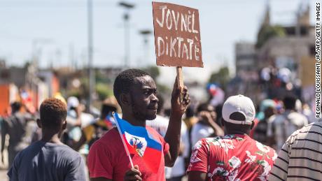 La gente sostiene carteles durante una manifestación en Puerto Príncipe el 14 de febrero de 2021.