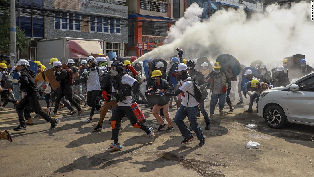 Anti-coup protesters run in Yangon on March 3. One of them discharged a fire extinguisher to counter the impact of tear gas fired by police.