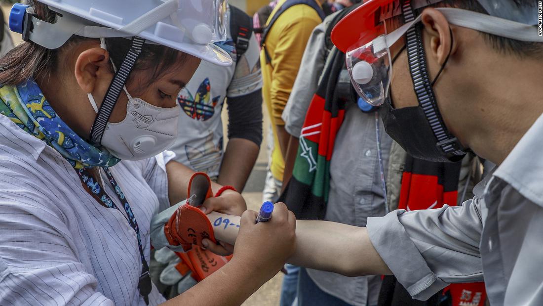 An anti-coup protester writes vital emergency information of another protester on his arm in Yangon.