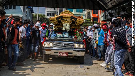People pay respects as the hearse carrying the coffin of Ma Kyal Sin drives on the street.
