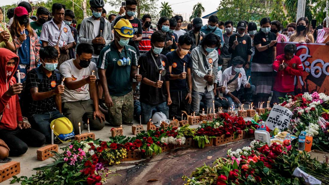 People lay flowers and light candles beside bloodied pavement where protester Chit Min Thu was killed in Yangon.