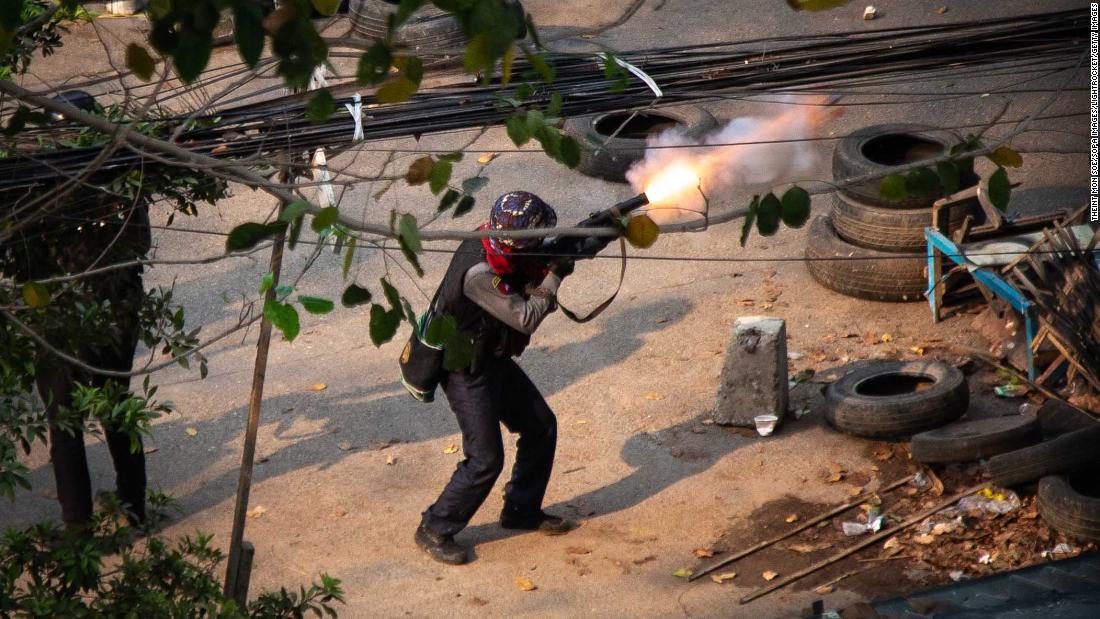 A member of Myanmar&#39;s police is seen firing a weapon toward protesters in Yangon on March 13.
