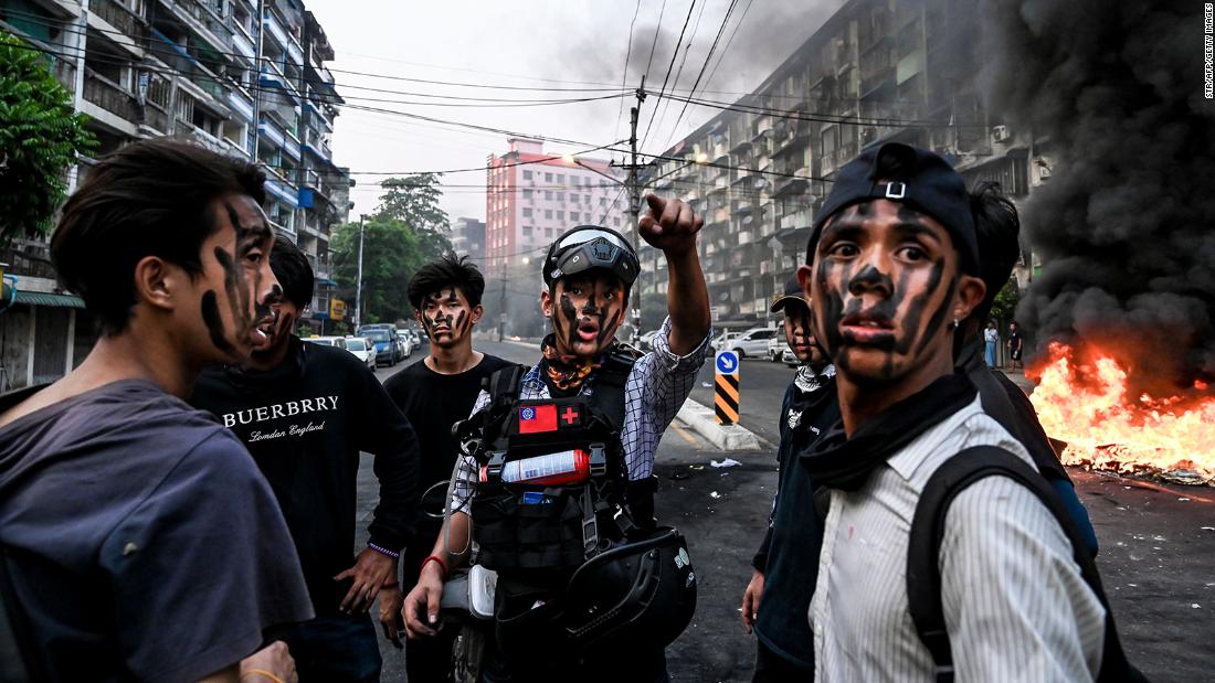 Protesters wearing face paint stand near a burning barricade during an anti-coup demonstration in Yangon on March 30.