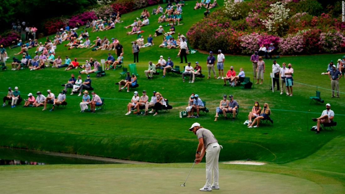 People spread out from one another as they watch Tommy Fleetwood putt on the 16th green on April 9.