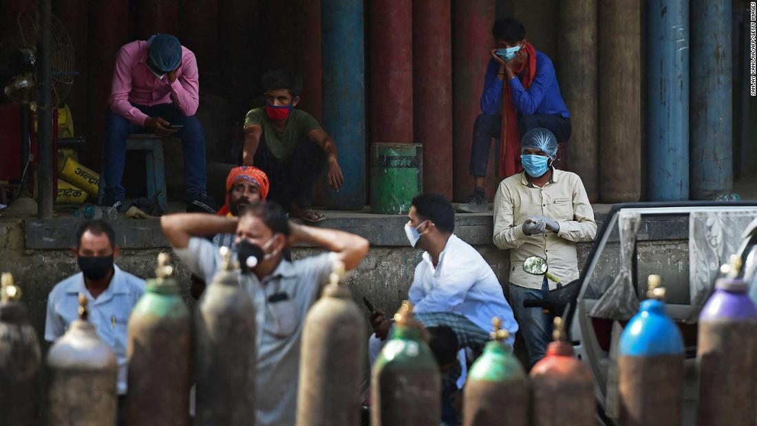 People wait to refill their oxygen cylinders at a refilling station in Allahabad on April 24.