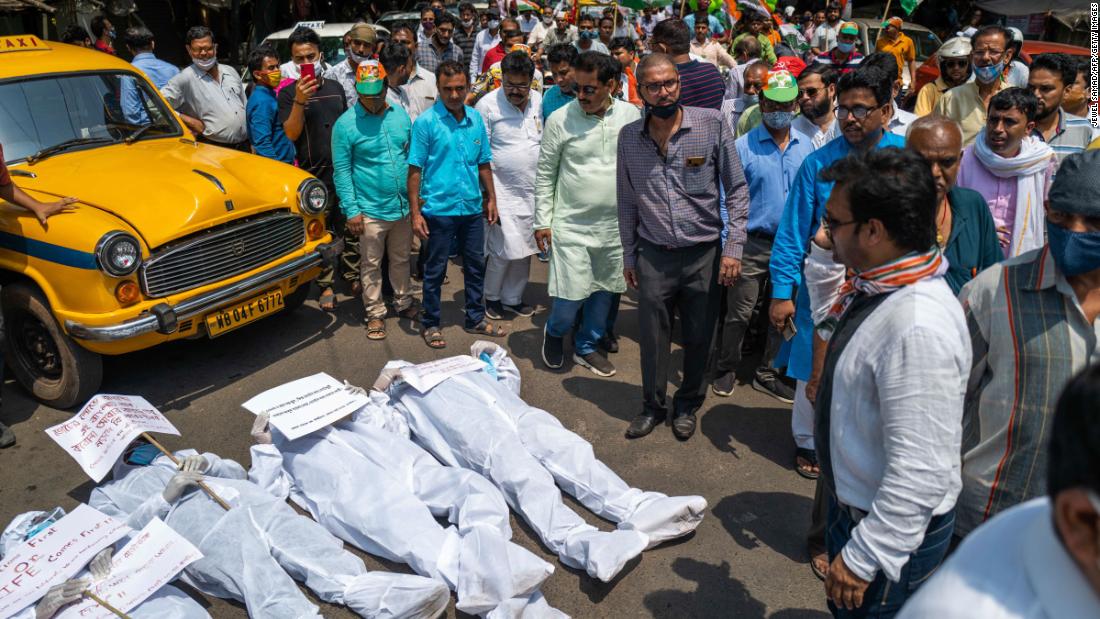 Protesters wearing protective suits lie on a street near the Election Commission office in Kolkata on April 7. They were calling for a stop to the ongoing state legislative election and its associated campaign rallies.