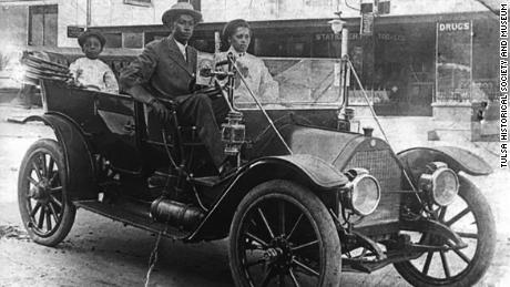 Reproduction, black &amp; white photograph measuring 5&quot; x 7&quot; of John Wesley Williams and wife, Loula Cotten Williams, and their son, William Danforth Williams, sitting in a 1911 Norwalk automobile. A sign advertising A. L. Black Printing Company, located at 114 S. Boston Ave, Tulsa, OK, is visible in the background. John was an engineer for Thompson Ice Cream Company. Loula was a teacher in Fisher. The Williams family owned the Dreamland Theatre, which opened in 1914 at 129 North Greenwood Avenue, and was destroyed in the 1921 Tulsa Race Massacre.