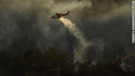 Firefighters keep a lookout as a Los Angeles Fire Department helicopter makes a water drop Saturday on the Palisades Fire in Topanga State Park.