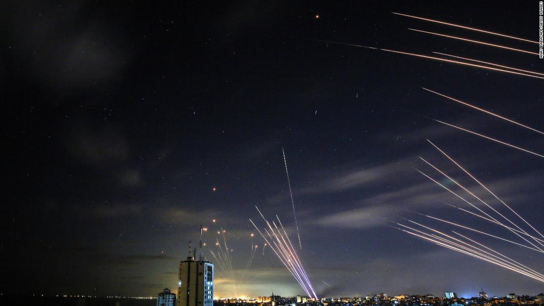 In the background, the Israeli Iron Dome aerial-defense system intercepts rockets fired by Hamas militants toward southern Israel on May 16.