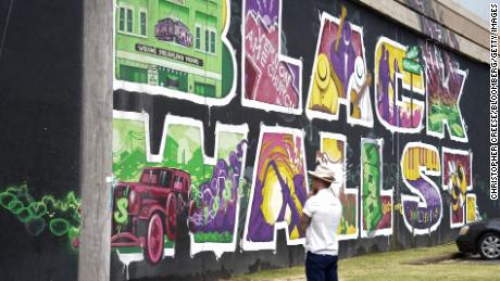 A pedestrian stands in front of the Black Wall Street Mural in the Greenwood District of Tulsa Oklahoma, U.S., on Friday, June 19, 2020. Greenwood, known as Black Wall Street, was one of the most prosperous African-American enclaves in the U.S. before the slaughter of its citizens. Today, a mere handful of Black-owned businesses operate on its single remaining block. Photographer: Christopher Creese/Bloomberg via Getty Images